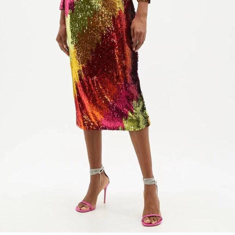 Hot pink ankle wrap sandals with diamond chain detailing, styled with a colorful sequin midi dress for a chic look.