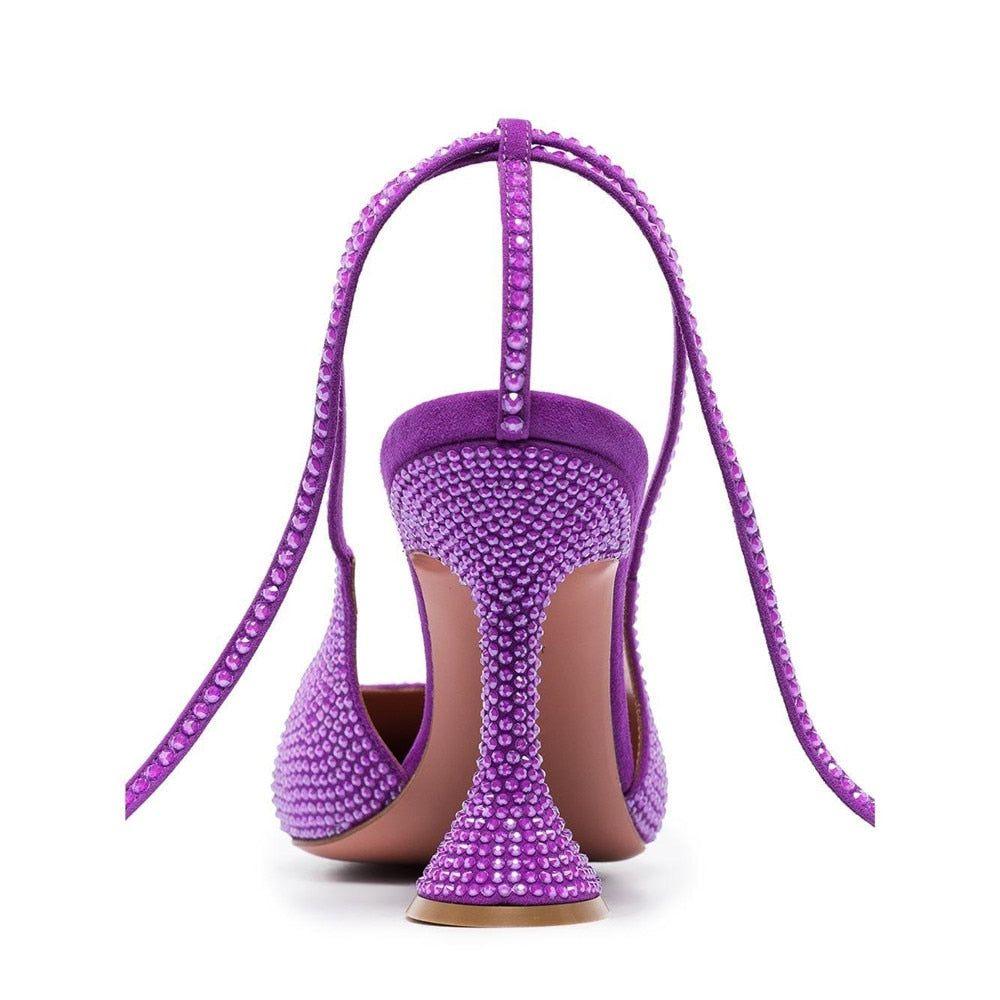 Purple high-heeled shoes with rhinestone embellishments on a white background