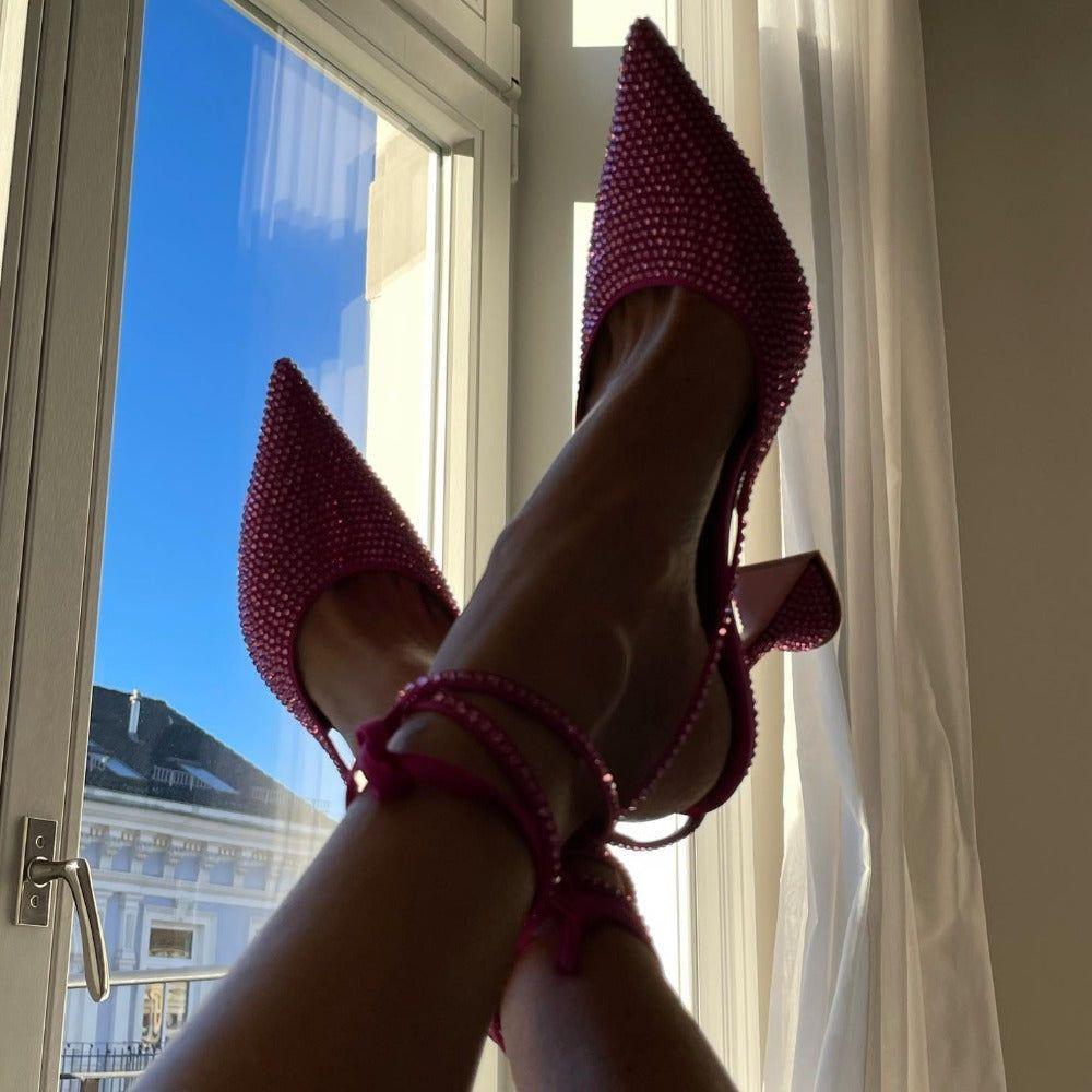 Pink beaded high heels being worn with a window and blue sky in the background