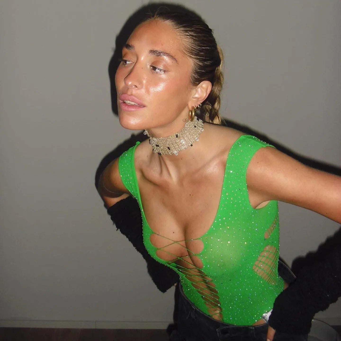 Green rhinestone-embellished bodysuit with a scoop neckline, styled with a choker and high-waisted jeans.