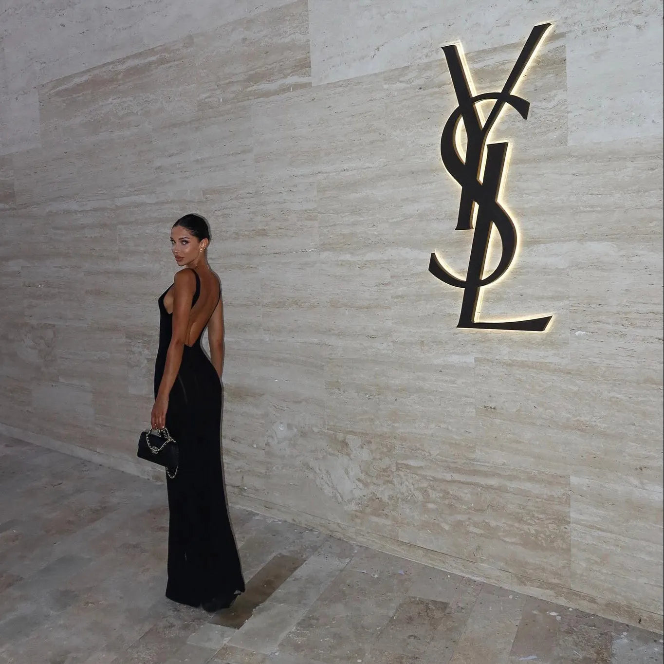 backless black evening gown with chain-strap handbag, elegant look