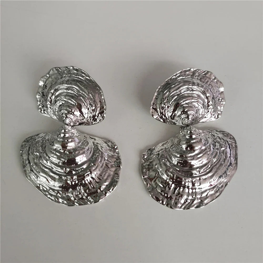 Pair of silver shell-shaped earrings on a gray background