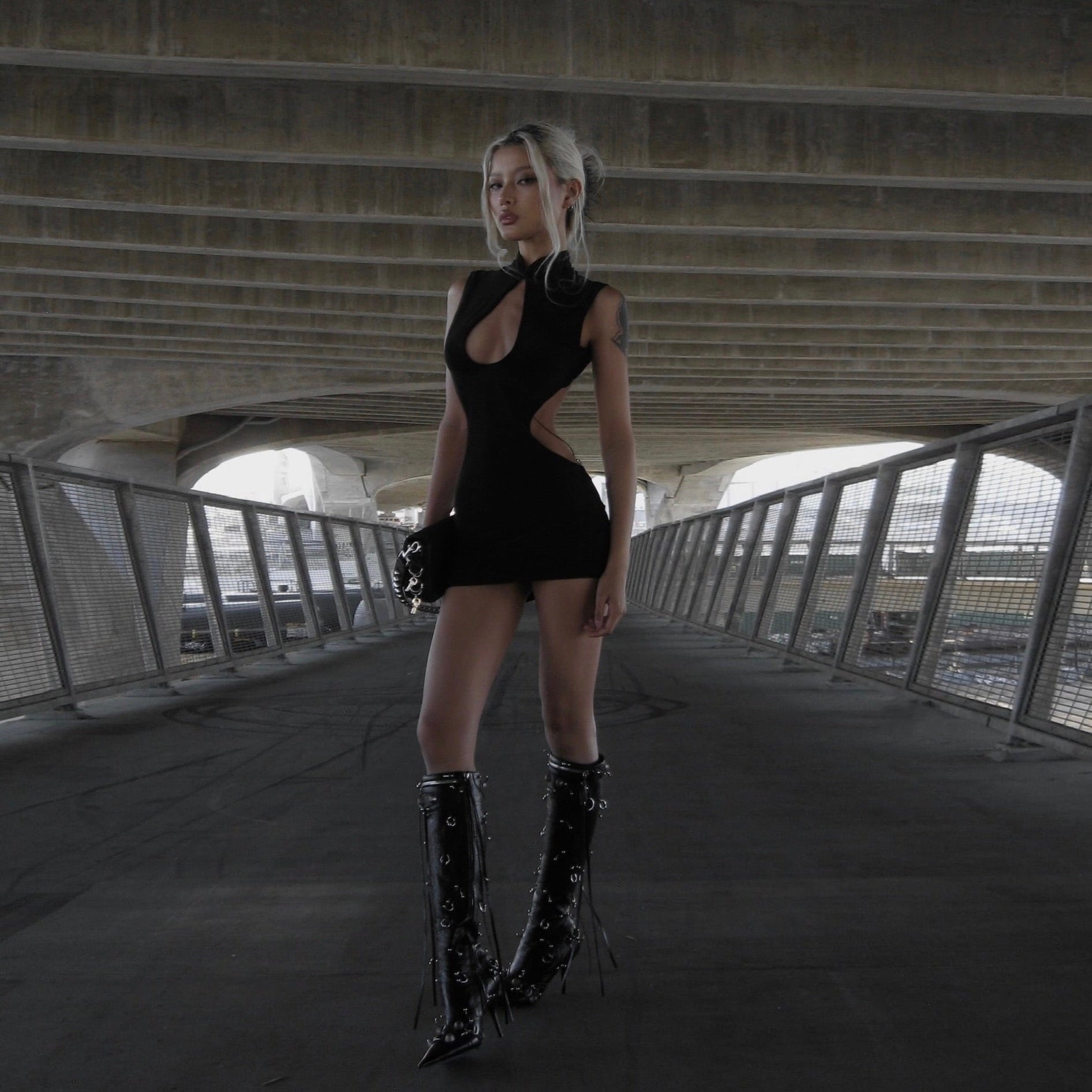 Black cut-out mini dress with high-heeled boots, ideal for a night-out.