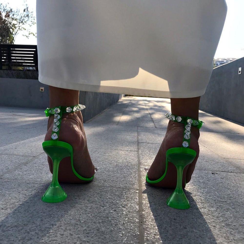 Person wearing brown shoes with green heel designs on a concrete surface.