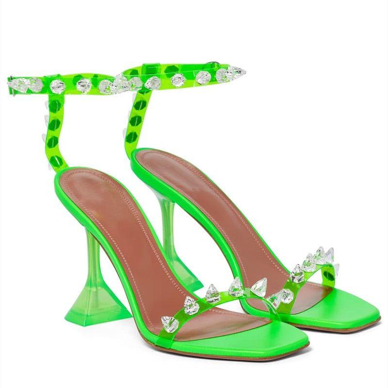 Green high-heeled sandals with crystal embellishments on a white background