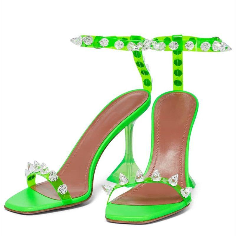 Neon green high-heeled shoes with crystal embellishments on a white background