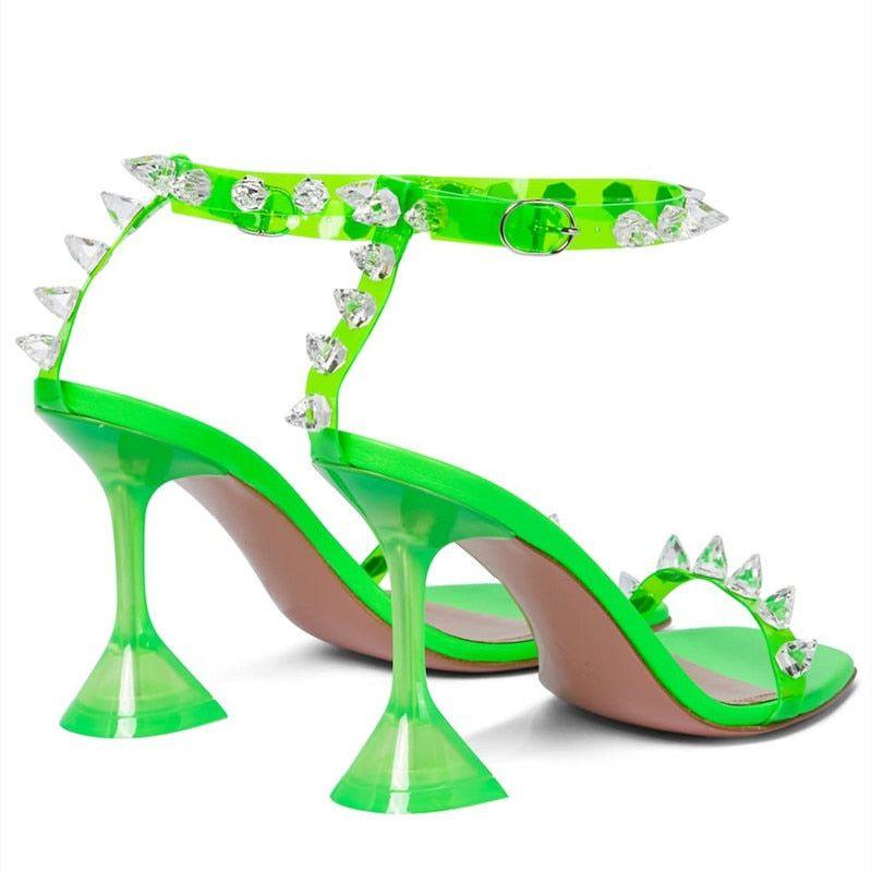 Green high-heeled shoes with spike details on a white background