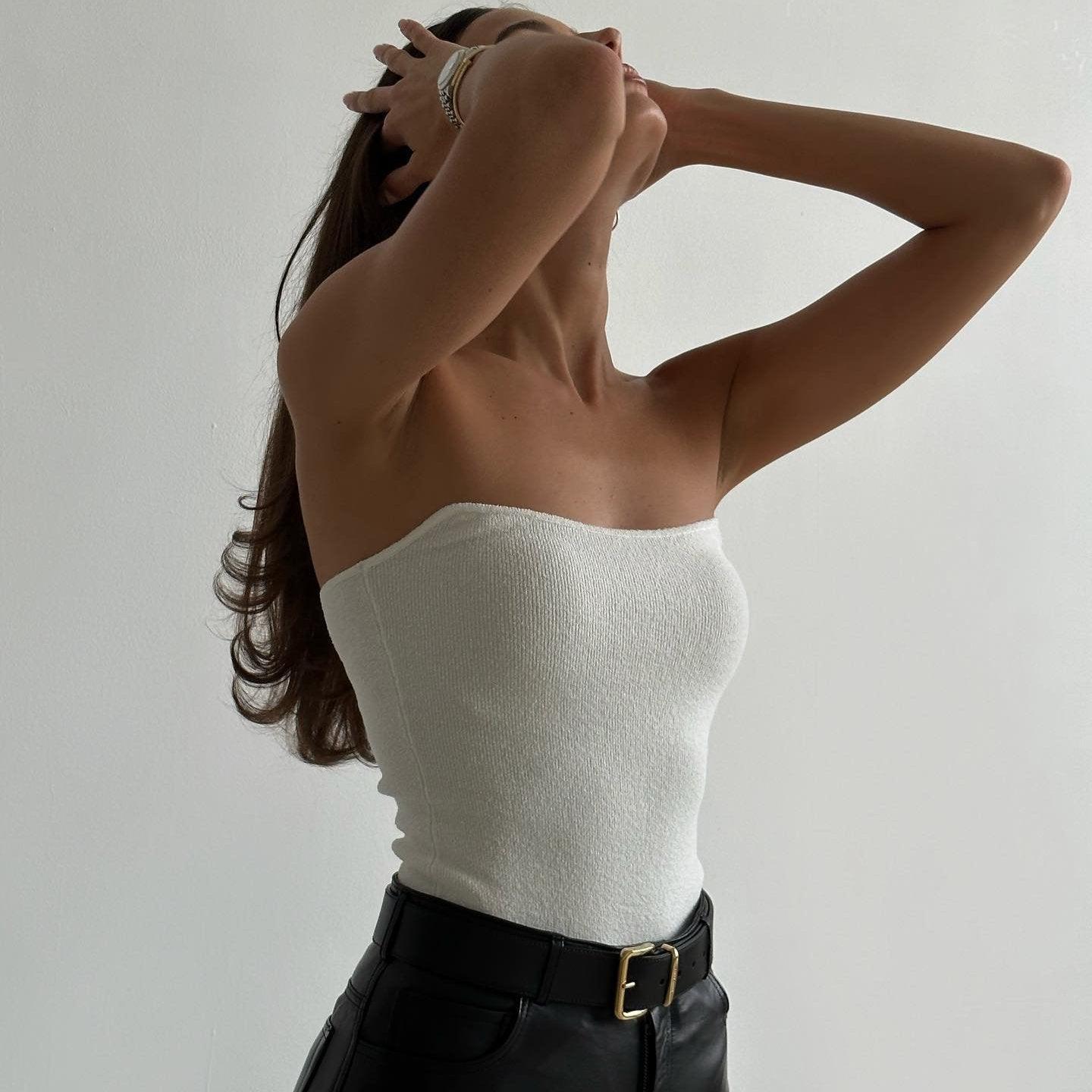 White knitted tube top with a fitted silhouette, styled with high-waisted black leather pants for a chic summer look.