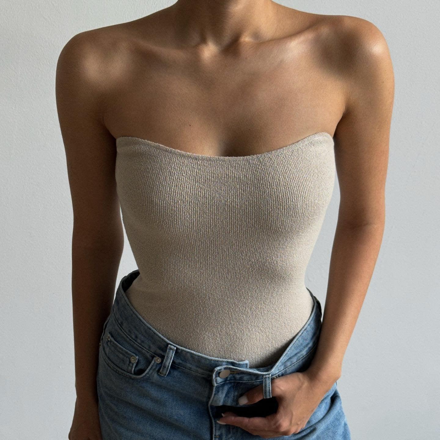Beige knitted tube top with a fitted silhouette, styled with high-waisted denim for a casual summer look.
