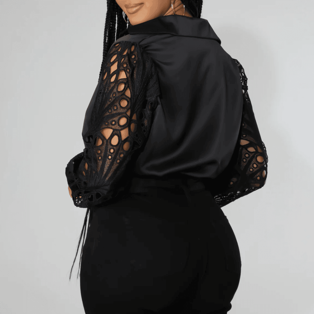 Elegant black satin blouse featuring intricate lace sleeves, styled with tailored pants for a chic, sophisticated look.