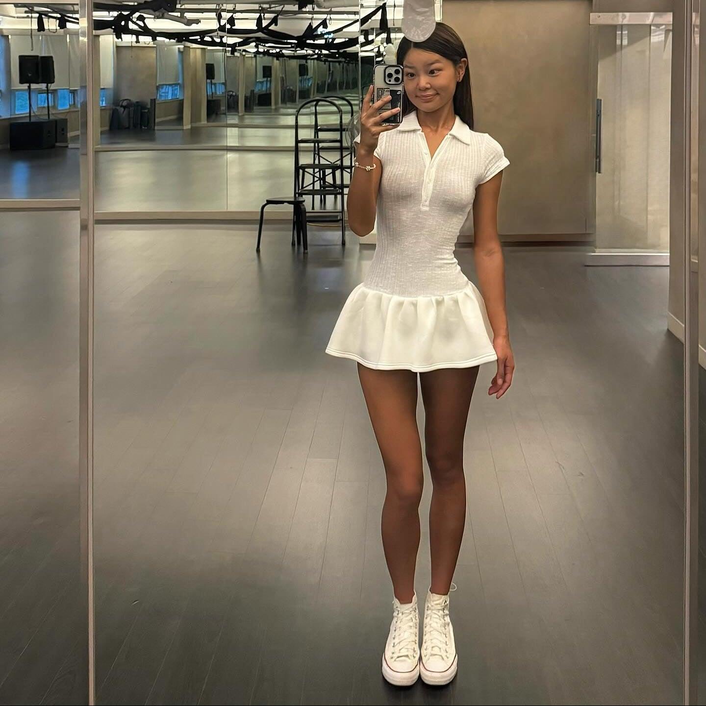 White polo style mini dress with a ribbed knit top and flared skirt, styled with white sneakers for a casual look.