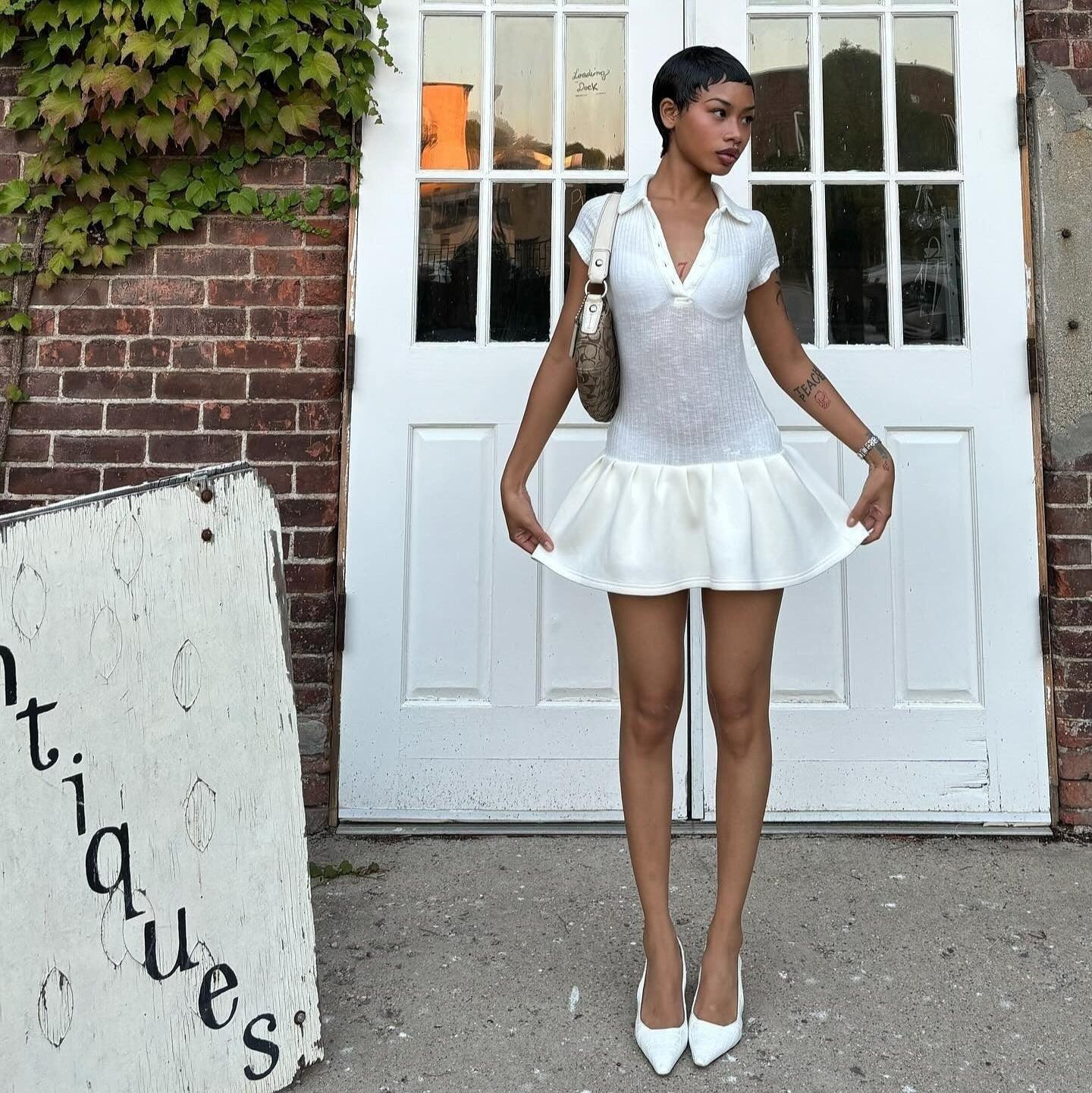 White mini dress with polo collar and flared hem, styled for a chic look paired with elegant heels.