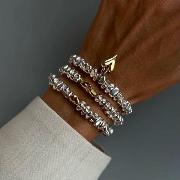 stacked silver and gold-toned bead bracelets with heart charm