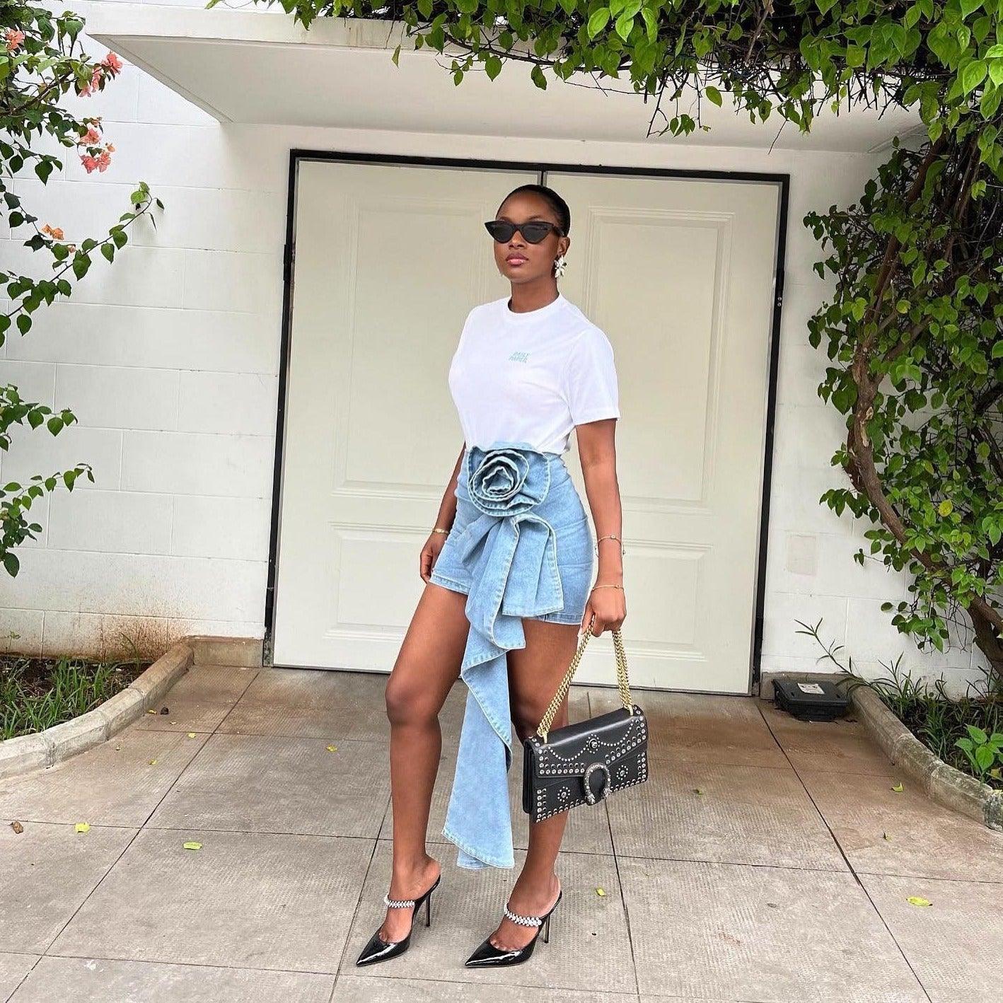 denim asymmetrical mini skirt with floral detail, paired with black studded handbag and pointed-toe