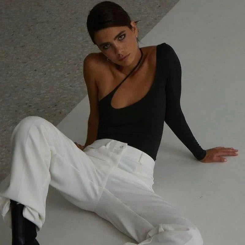 black one-shoulder top with cutout, paired with white pants