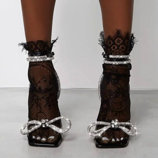 Black lace heels with rhinestone bows and ankle detailing.