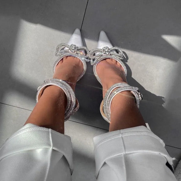 White pointed heels with crystal embellishments, perfect for evening wear.